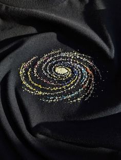 a black fabric with multicolored beads on the center and an embroidered circle in the middle