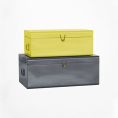 two boxes sitting on top of each other in front of a white background, one yellow and the other gray