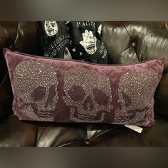 two decorative pillows sitting on top of a brown leather couch next to a black and white pillow