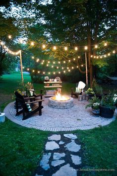 an image of a fire pit in the middle of a yard with lights strung over it