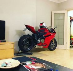 a red motorcycle is parked in the living room next to a flat screen tv and entertainment center