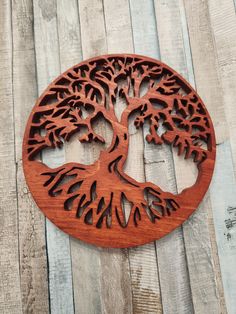 a wooden wall hanging with a tree cut out in the shape of a circle on top of wood planks