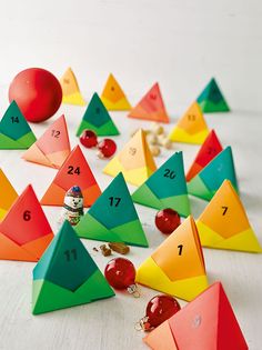 a group of colorful paper pyramids sitting on top of a white table next to an apple