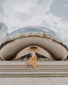 a woman is sitting on the steps in front of a large object that looks like a building