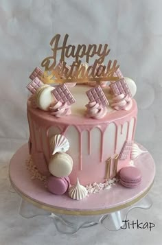 a pink and white birthday cake sitting on top of a table