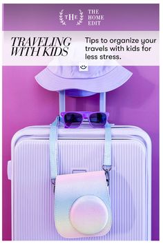 a white suitcase with sunglasses and hat hanging on it's side next to a purple wall