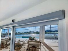 a living room filled with furniture next to a large glass window overlooking a pool and mountains