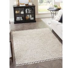 a living room with a white couch and a rug on the floor in front of a window