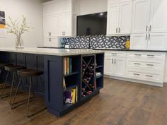 a kitchen with white cabinets and an island in front of two bar stools next to it