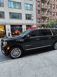 a black suv is parked on the side of the road in front of a building