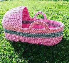 a pink crocheted baby's bassinet in the grass