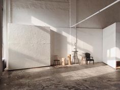 an empty room with two chairs and a table in the middle, against a white wall