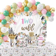 a table topped with balloons and desserts next to a sign that says two wild