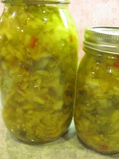 two jars filled with pickles sitting on top of a counter