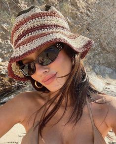 a woman wearing sunglasses and a hat on the beach