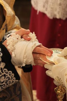 the hands of two people dressed in old fashioned clothing and holding a small child's hand