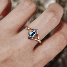 a woman's hand with a gold ring and blue topazte stone on it