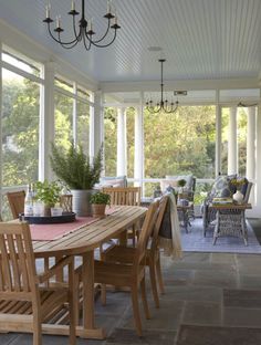 a dining room table with chairs and potted plants on top of it in front of an open porch