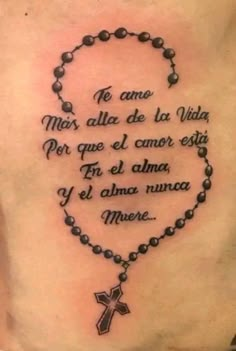 the back of a woman's chest with a rosary and cross tattoo on it