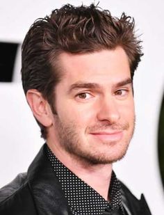 a close up of a person wearing a black jacket and polka dot shirt with his hair pulled back