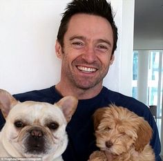 a man holding three small dogs in his arms and smiling at the camera while standing next to him