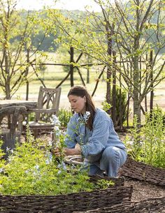 a woman kneeling down in the middle of a garden