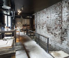 the interior of a restaurant with exposed brick and steel railings, along with tables and chairs