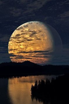 the full moon is setting over a lake