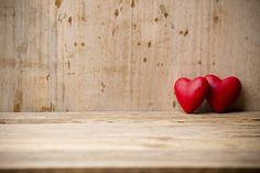 two red hearts sitting on top of a wooden shelf