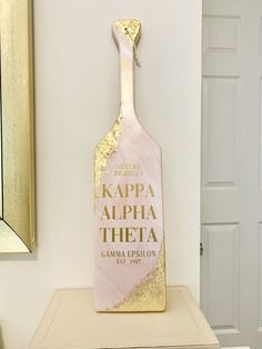 a pink and gold wine bottle on top of a dresser