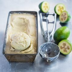 an ice cream in a metal container next to limes and a scoop of ice cream