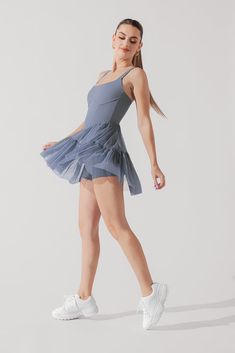 a woman in a blue dress and white tennis shoes