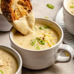 two bowls filled with soup and one has a piece of bread sticking out of it