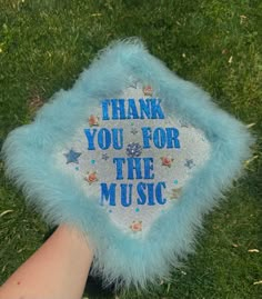 a hand holding a blue furry object that says thank you for the music