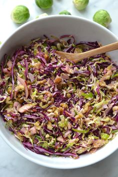 a white bowl filled with coleslaw next to brussels sprouts and walnuts