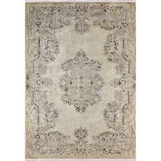 an antique rug with floral design on the front and side, in grey tones against a white background