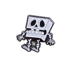 a silver and black lapel with a skeleton on it's face, sitting in front of a white background