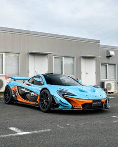 a blue and orange sports car parked in front of a building