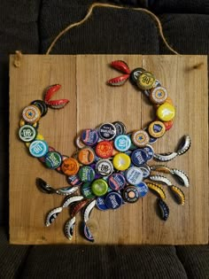 a crab made out of beer bottle caps sitting on top of a wooden board with string