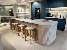 a kitchen with an island and stools in front of the counter top, surrounded by blue cabinets