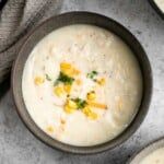 two bowls filled with soup and garnished with corn on the top, next to some bread