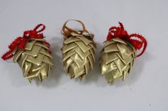 three gold ornaments with red ribbons on them