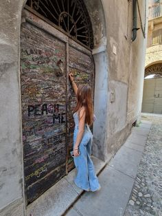 a woman is standing in front of a door with writing on it and pointing to the side