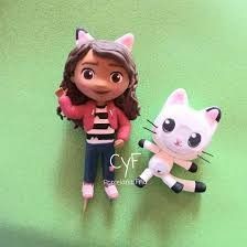 two small dolls are sitting next to each other on a green surface, one has a black and white cat