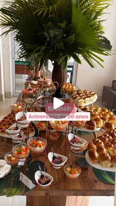 a table filled with lots of food on top of a wooden table next to a potted plant