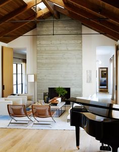 a living room filled with furniture and a piano in front of a wall mounted fireplace