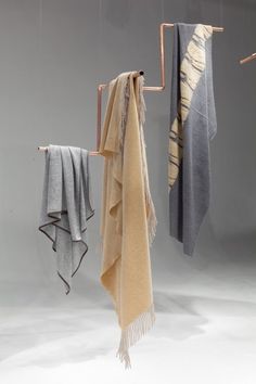 three towels hanging from hooks in the air with one folded and two un - draped