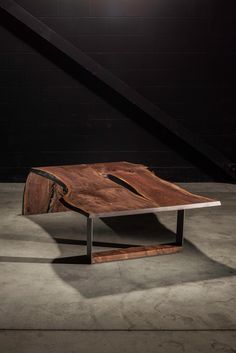 a table made out of wood and metal in the middle of a room with a black wall behind it