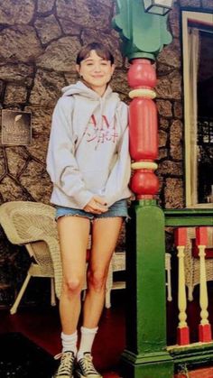 a young woman standing next to a green and red pole