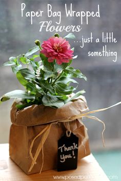 a flower in a paper bag with a thank you tag attached to it that says, paper bag wrapped flowers just a little something